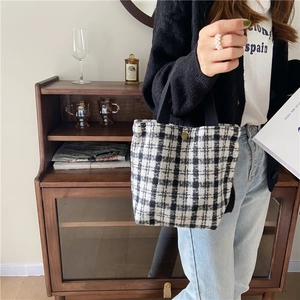 Detailed view of a vintage black and white plaid wool bento bag held in a model's hand.