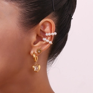 Détail de boucles d'oreilles dorées 18K avec cœur, bagues d'oreille en perles et clou soleil