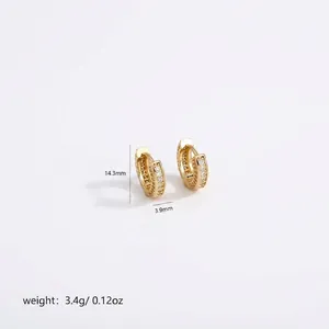 Detailed view of gold huggie earrings with triple-row cubic zirconia inlay, 14.3mm height