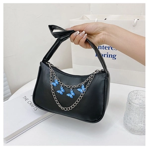 Detail of black shoulder bag with silver chain and blue butterfly pendants