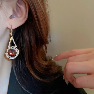 Détail d'une boucle d'oreille dorée avec pierre précieuse rouge et zircons baguettes