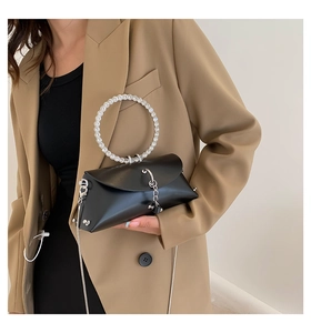 Detail of elegant black handbag featuring a sparkling rhinestone circular handle and chain strap
