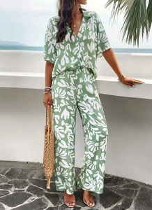 Close-up of women's two-piece green floral short sleeve shirt and trouser resort set