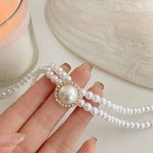 Gros plan d'un collier de perles baroques double rangée avec centre en strass brillants