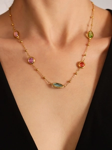 Gros plan d'un collier doré avec des pierres précieuses colorées sur le cou d'un mannequin