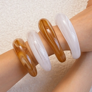 Detail of layered acrylic bangles with white marble and amber resin textures on wrist