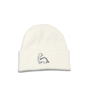 Detailed view of black dinosaur embroidery on a white knitted beanie cuff