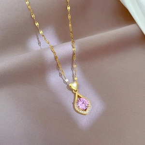 Détail du collier cœur doré avec pendentif gemme rose sur tissu beige doux