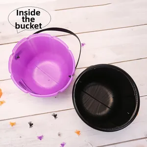 Top view of purple and black Halloween candy buckets with handles on a white wooden surface