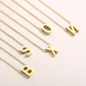 Macro view of gold stainless steel necklace chains with uppercase initial letter pendants