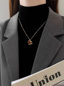 Close-up of model wearing 18K gold horse necklace with red enamel pendant and zircon detail