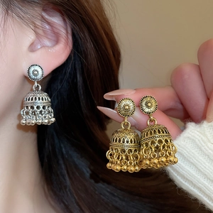 Detail of vintage carved bell earrings with metal tassels in silver and gold finishes