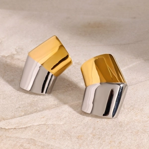 Macro view of minimalist two-tone gold and silver geometric studs on a textured stone