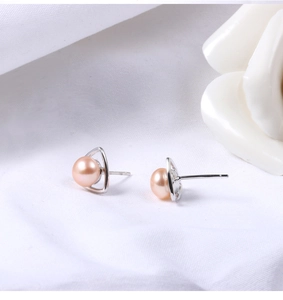 Detailed view of natural pink freshwater pearls set in silver triangle earrings on white fabric