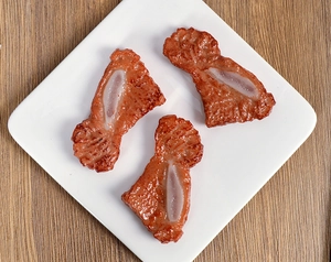 Detailed top view of realistic faux lamb chops with meat texture in a white tray