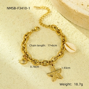 Close-up of gold chunky chain bracelet with starfish and seashell charms on sand