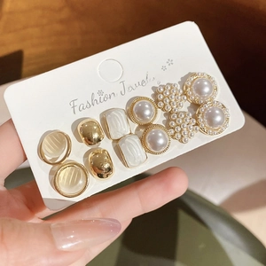 Detailed close-up of 12-piece gold pearl and gemstone earring set on fashion jewelry card