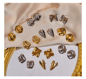 Detailansicht geometrischer unregelmäßiger Metallohrringe in poliertem Gold und Silber