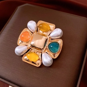 Baroque vintage gold cross brooch with colorful gemstones and pearls on velvet box