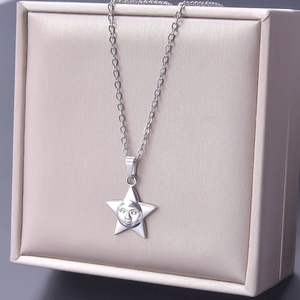 Detailed view of silver star pendant necklace with embossed face in beige jewelry box