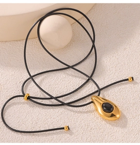 Macro detail of gold teardrop pendant with black onyx inlay on stylish wax cord