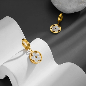 Boucles d'oreilles trèfle en titane doré avec nacre blanche sur des cubes blancs