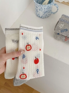 Close-up of white breathable mesh socks with red apple pattern and blue text