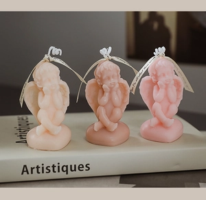 Detailed view of three handcrafted angel scented candles in beige and pink on a book