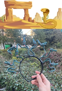 Detail of dark green Medusa snake headband with multiple serpents and red eyes