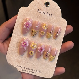 Close-up of 3D embossed floral press-on nails with gold foil and pearl accents