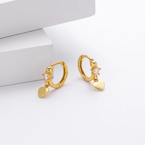 Close-up of heart charm earrings in gold finish with a single sparkling zircon stone