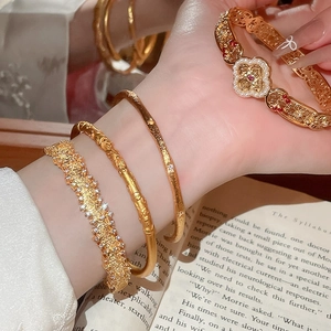 Macro detail of a gold flower cuff bracelet with red gemstones and pearl accents