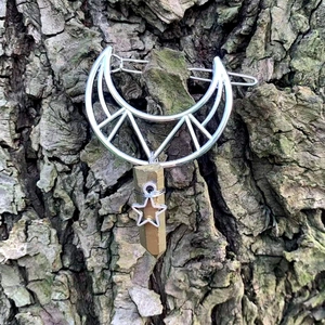 Macro detail of hollow moon hair clip with wire-wrapped crystal on natural tree bark background