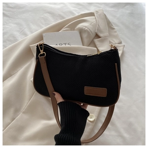 Detail of vintage black corduroy underarm bag with brown leather strap and rectanglular tag
