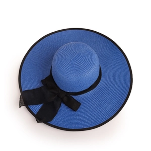Detail of royal blue straw hat featuring woven texture and a black ribbon bow decoration