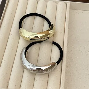 Detail of minimalist gold and silver crescent hair ties on a soft beige velvet tray