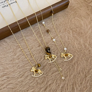Macro shot of gold rocking horse pendant with tiger eye stone and small diamond details
