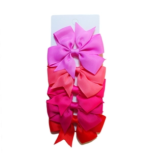 Set of four gradient pink and red ribbed ribbon hair bows displayed on a white card