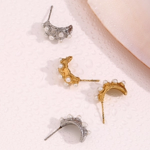 Gros plan de boucles d'oreilles demi-cercles or et argent avec perles sur fond de texture d'eau