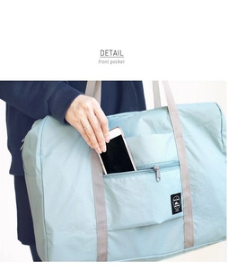 Detail view of the front zipper pocket on a light blue travel bag for phone storage