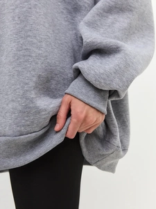 Detail view of ribbed cuffs and hem on a gray oversized fleece sweatshirt