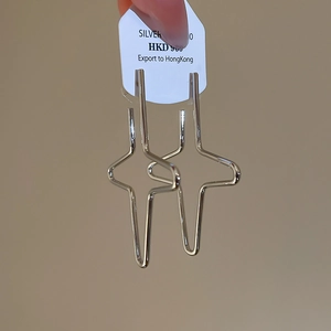 Detailed macro view of S925 sterling silver geometric cross star earrings on a card