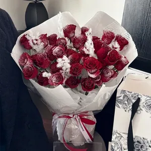 Bouquet di rose rosse scure con polvere di neve e confezione regalo bianca elegante
