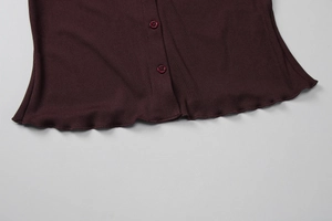 Détail macro du tricot côtelé bordeaux avec boutons assortis et bordure de l'ourlet ondulé