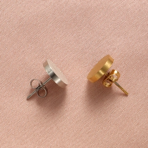 Close-up of gold and silver round brushed titanium steel earrings with butterfly backs