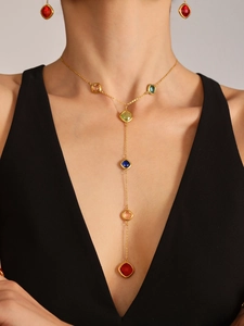 Dettaglio dell'elegante collana a Y dorata con pietre preziose colorate su modella