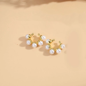 Detail shot of C-shaped gold-plated ear cuffs featuring five inlaid small white pearls