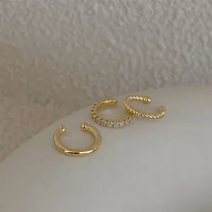 Lot de trois ear cuffs dorés aux textures lisses, pavées de zircons et torsadées