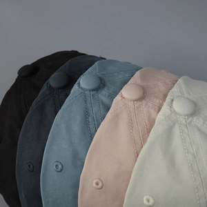 Close-up of stacked cotton baseball caps in multiple colors showing texture and stitching
