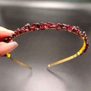 Detail of handmade gold wire headband with raw red garnet crystals held by hand